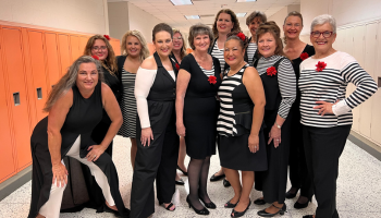 A group of women in black and white outfits stand together in a group smiling
